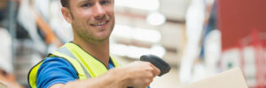 Smiling manual worker scanning package in warehouse