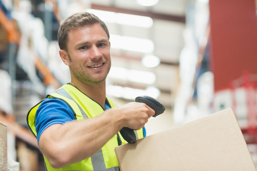 Smiling manual worker scanning package in warehouse