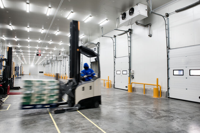 Worker Stand-on stacker truck used to lift and move the boxes in warehouses 