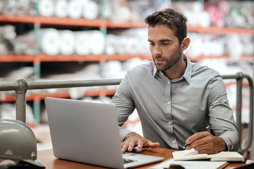 manager at eCommerce warehouse checking out orders on laptop 