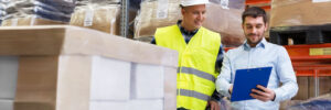 Two workers in warehouse going over warehouse insurance package