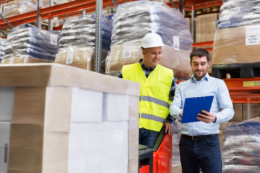 Two workers in warehouse going over warehouse insurance package