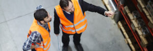 Warehouse workers working together while pointing at shelves