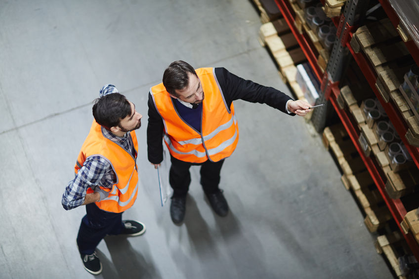 Warehouse workers working together while pointing at shelves