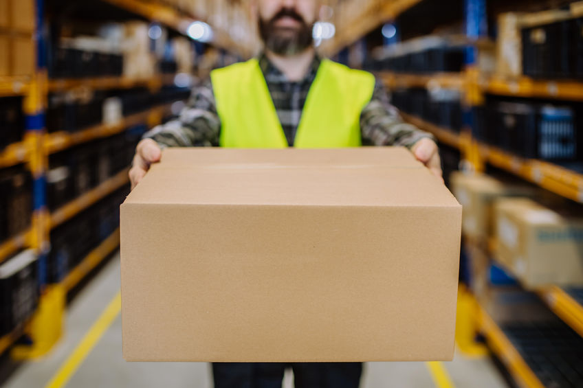 Close-up of warehouse worker packaging goods in warehouse.