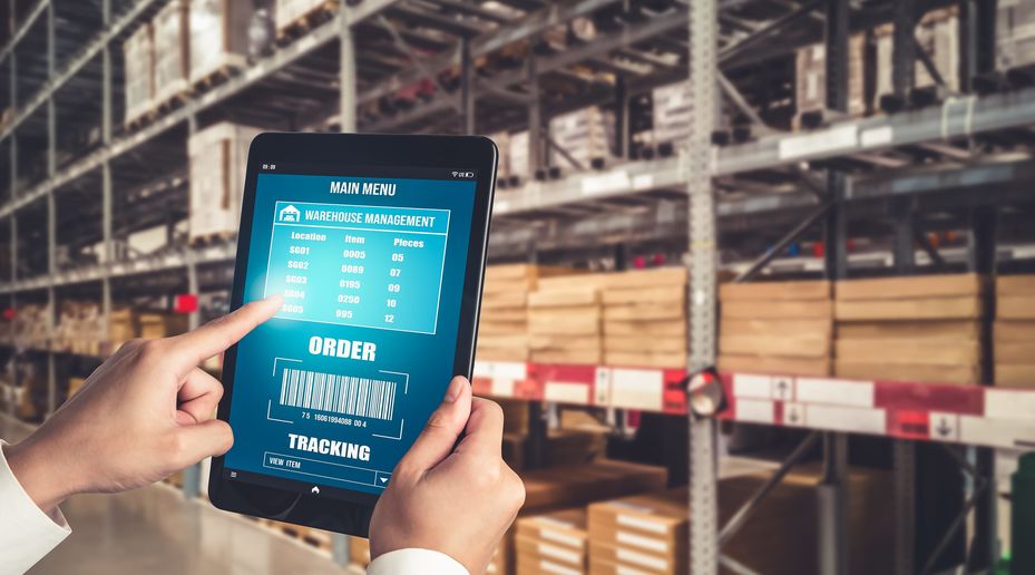 Tablet showing a real time inventory chart as a worker holds it in a warehouse