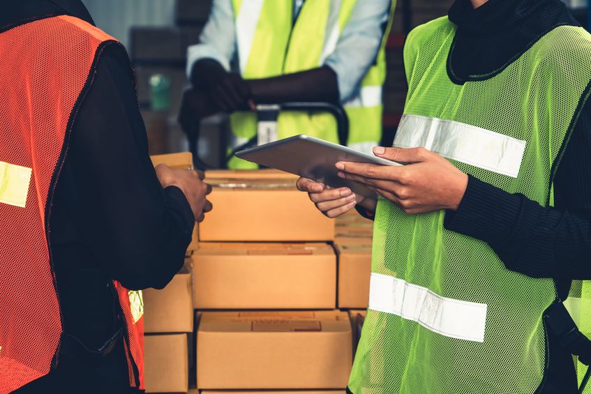 Warehouse workers working together on a box of returns. 