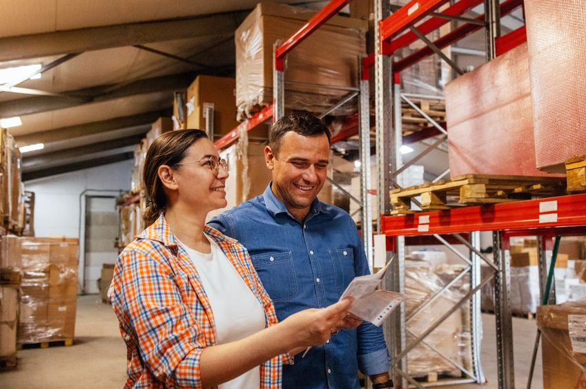 Smiling man and woman in warehouse looking at lease document