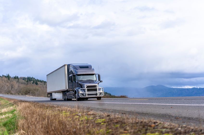 Truck hauling a load on a road under the beautiful sun.