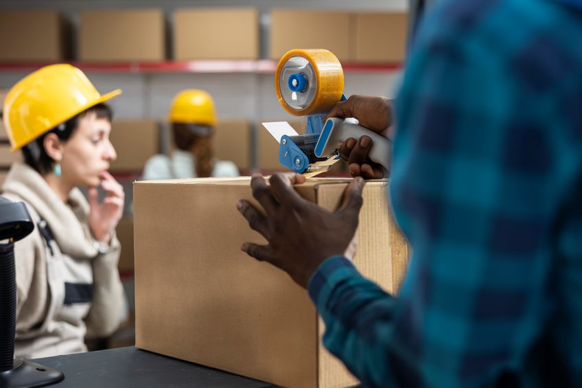 Employee at warehouse is packaging up a box